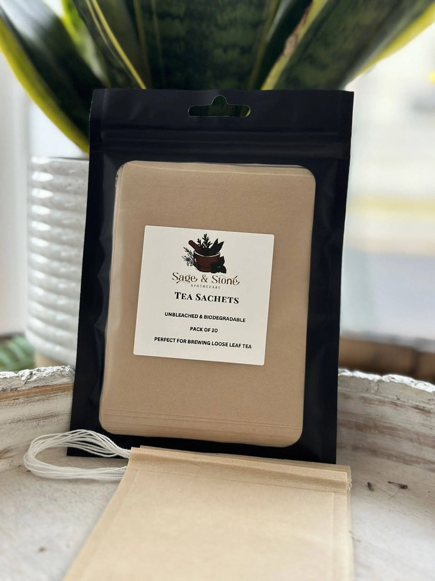 Tea sachets in a black package with a visible brand label on a wooden surface. -Clover's Charm