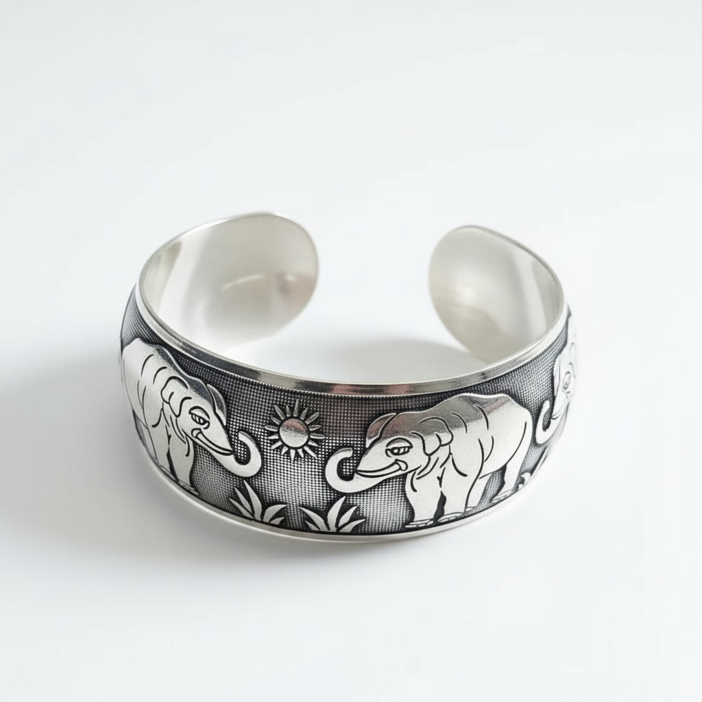 Silver bracelet with elephant designs on a dark surface