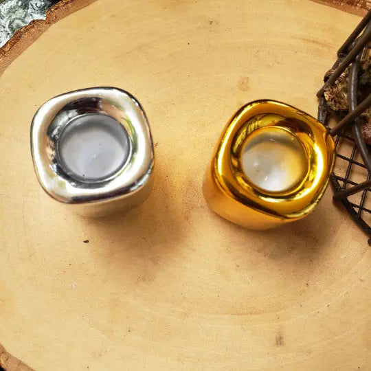 Two metallic candle holders, one silver and one gold, on a wooden surface - Clover's Charm