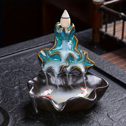Front view lotus blue ceramic incense burner with a cone incense burning and incense smoke flowing down like a waterfall. Twin fish detailing at the basin base
