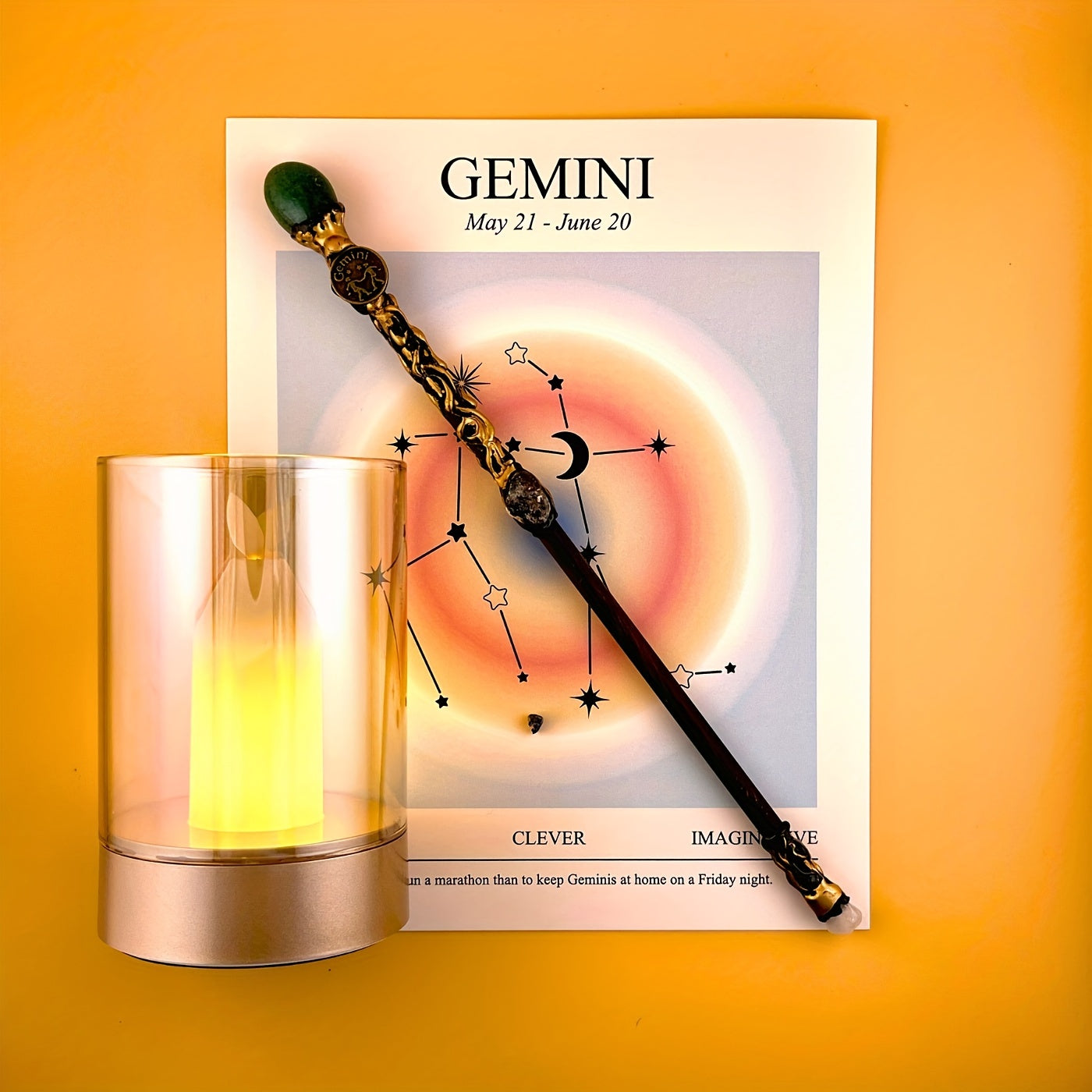 Gemini zodiac art print with constellation design displayed beside a glass candle holder and decorative astrology wand on a warm yellow background