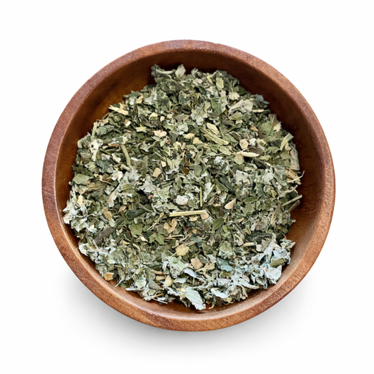 Wooden bowl filled with happy hormone balance tea dried herbs on a white background. -Clover's Charm