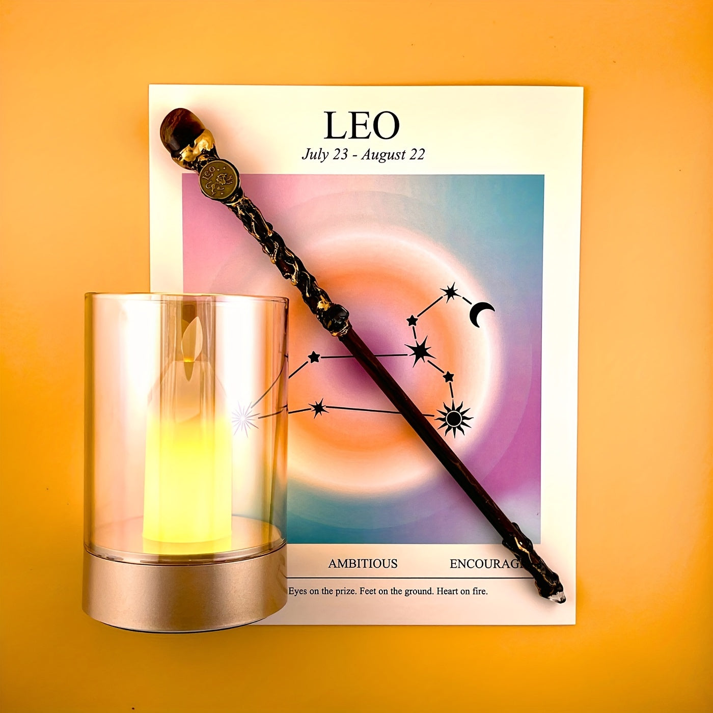 Leo zodiac art print with constellation design displayed beside a glass candle holder and decorative astrology wand on a warm yellow background