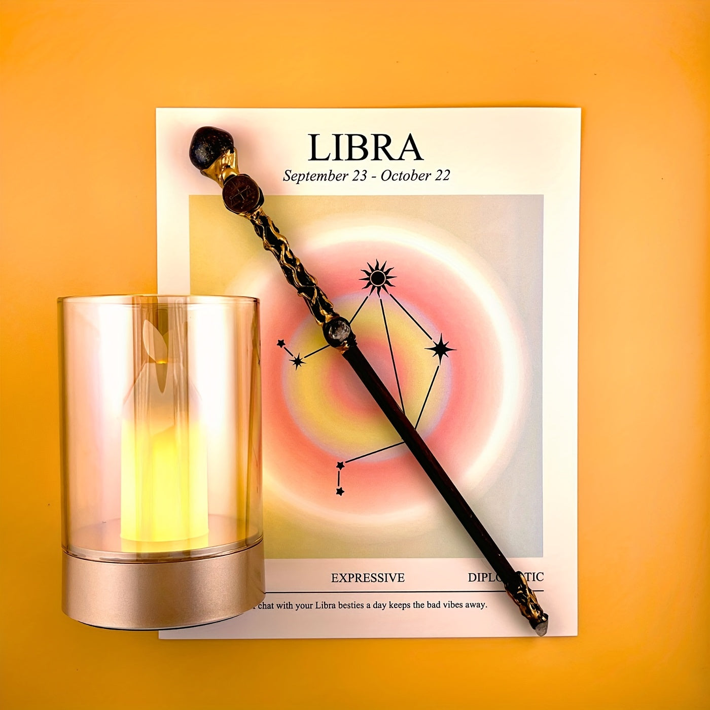 Libra zodiac art print with constellation design displayed beside a glass candle holder and decorative astrology wand on a warm yellow background
