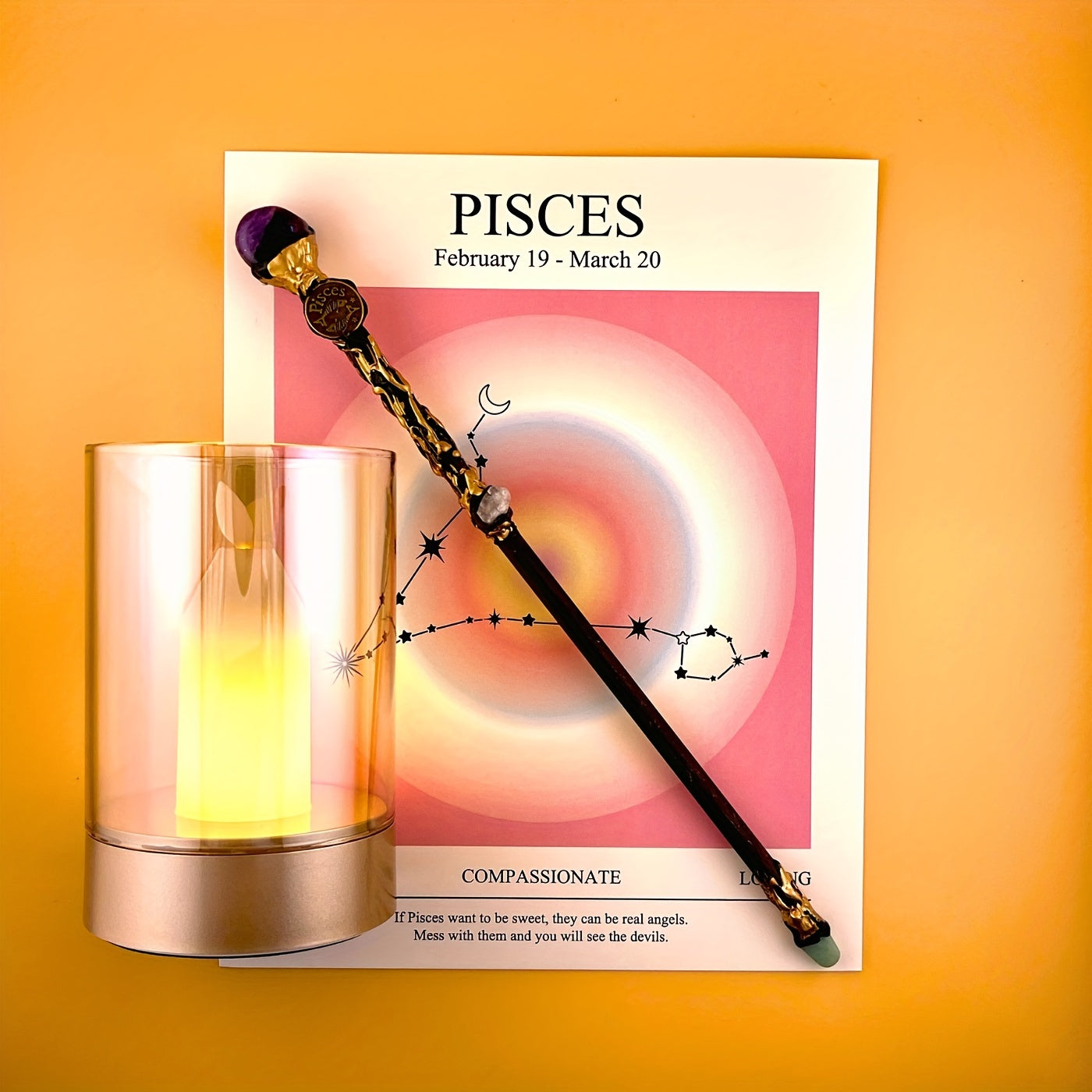 Pisces zodiac art print with constellation design displayed beside a glass candle holder and decorative astrology wand on a warm yellow background