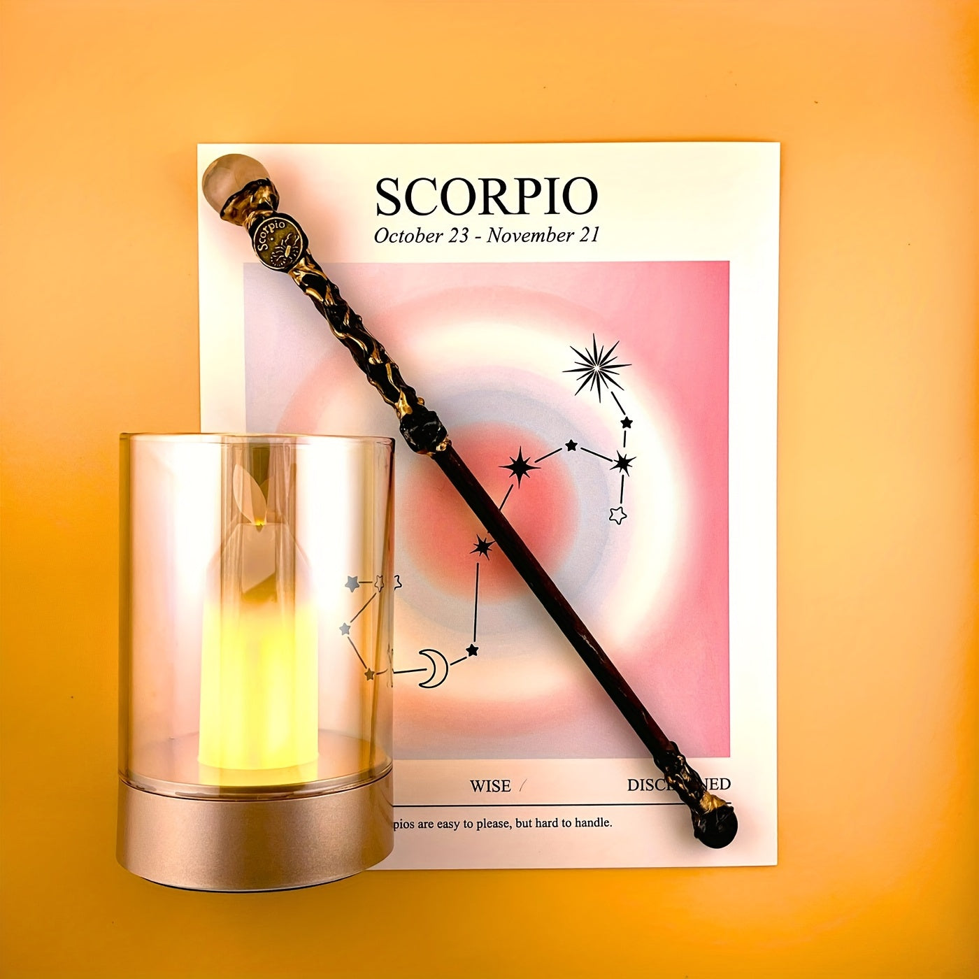 Scorpio zodiac art print with constellation design displayed beside a glass candle holder and decorative astrology wand on a warm yellow background