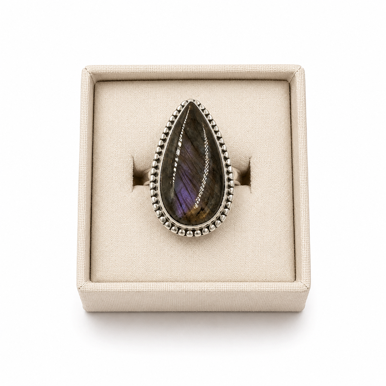 Sterling silver pear-shaped labradorite ring with beaded bezel displayed in a soft linen jewelry box on a white background -Clover's Charm.