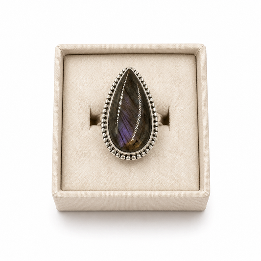 Sterling silver pear-shaped labradorite ring with beaded bezel displayed in a soft linen jewelry box on a white background -Clover's Charm.