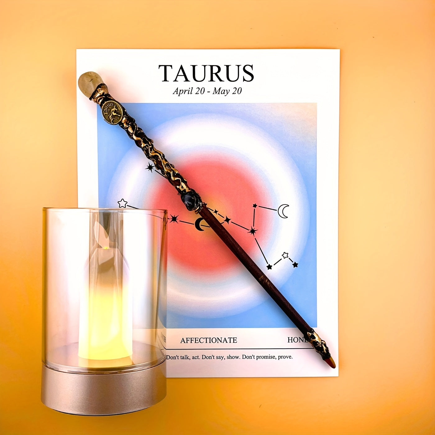 Taurus zodiac art print with constellation design displayed beside a glass candle holder and decorative astrology wand on a warm yellow background