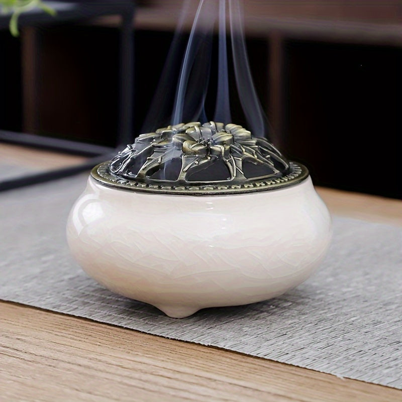 White ceramic incense burner with decorative metal lid displayed on a wooden surface against a dark background for elegant home decor styling smoke