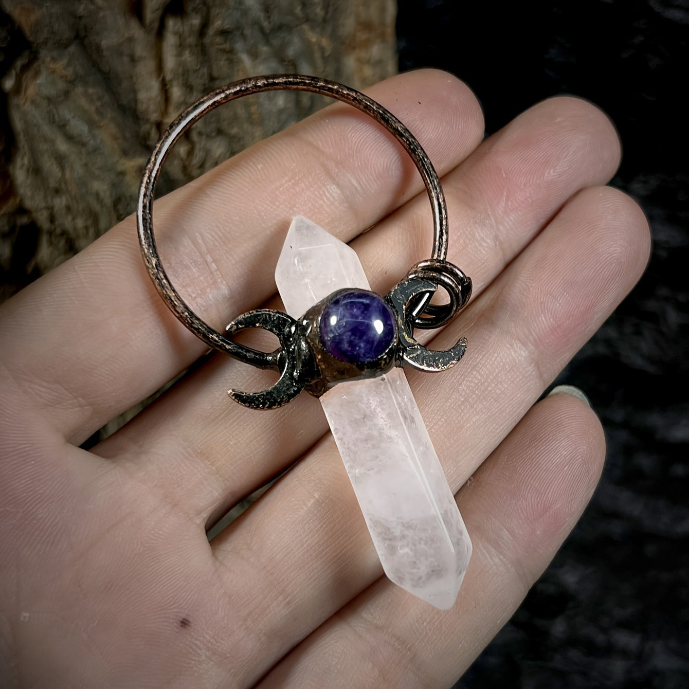 White natural crystal point moon pendant charm with faceted rock crystal and vintage style boho metal accent being held in the palm of a hand