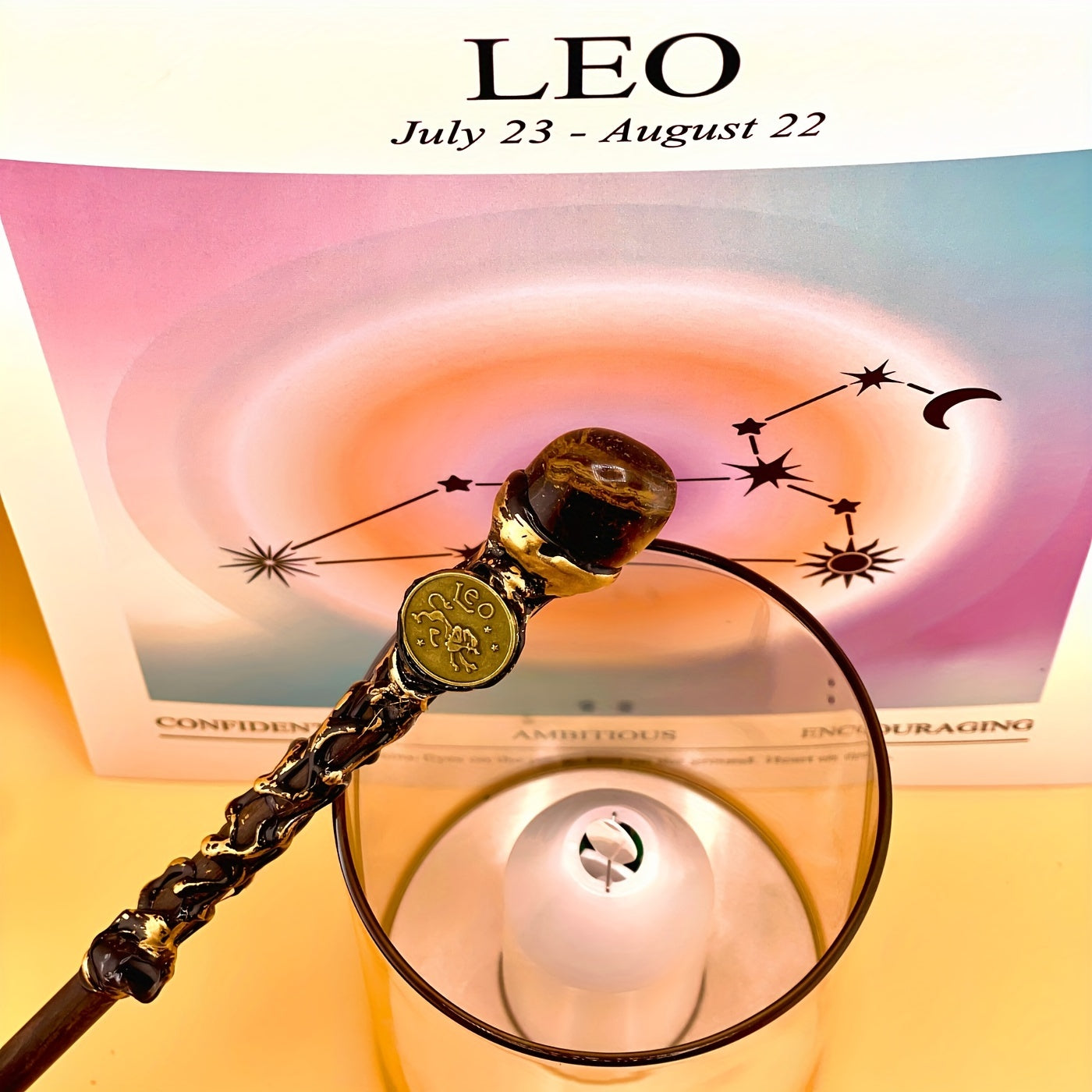 Leo zodiac art print with constellation design displayed behind a glass candle holder and decorative astrology wand on a warm yellow background