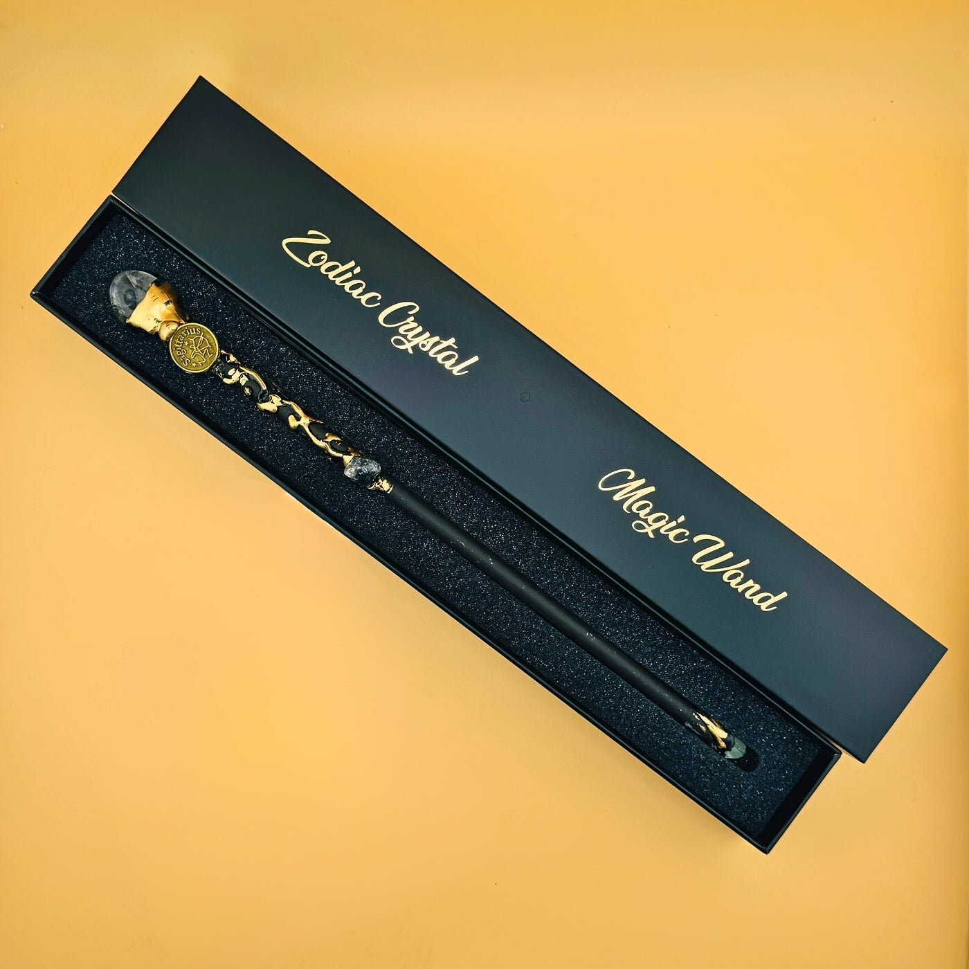 Zodiac crystal magic wand presented in a black gift box with gold lettering, displayed on a warm yellow background