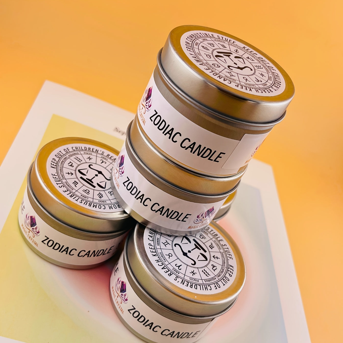 Stack of zodiac candles with decorative labels on a gradient background