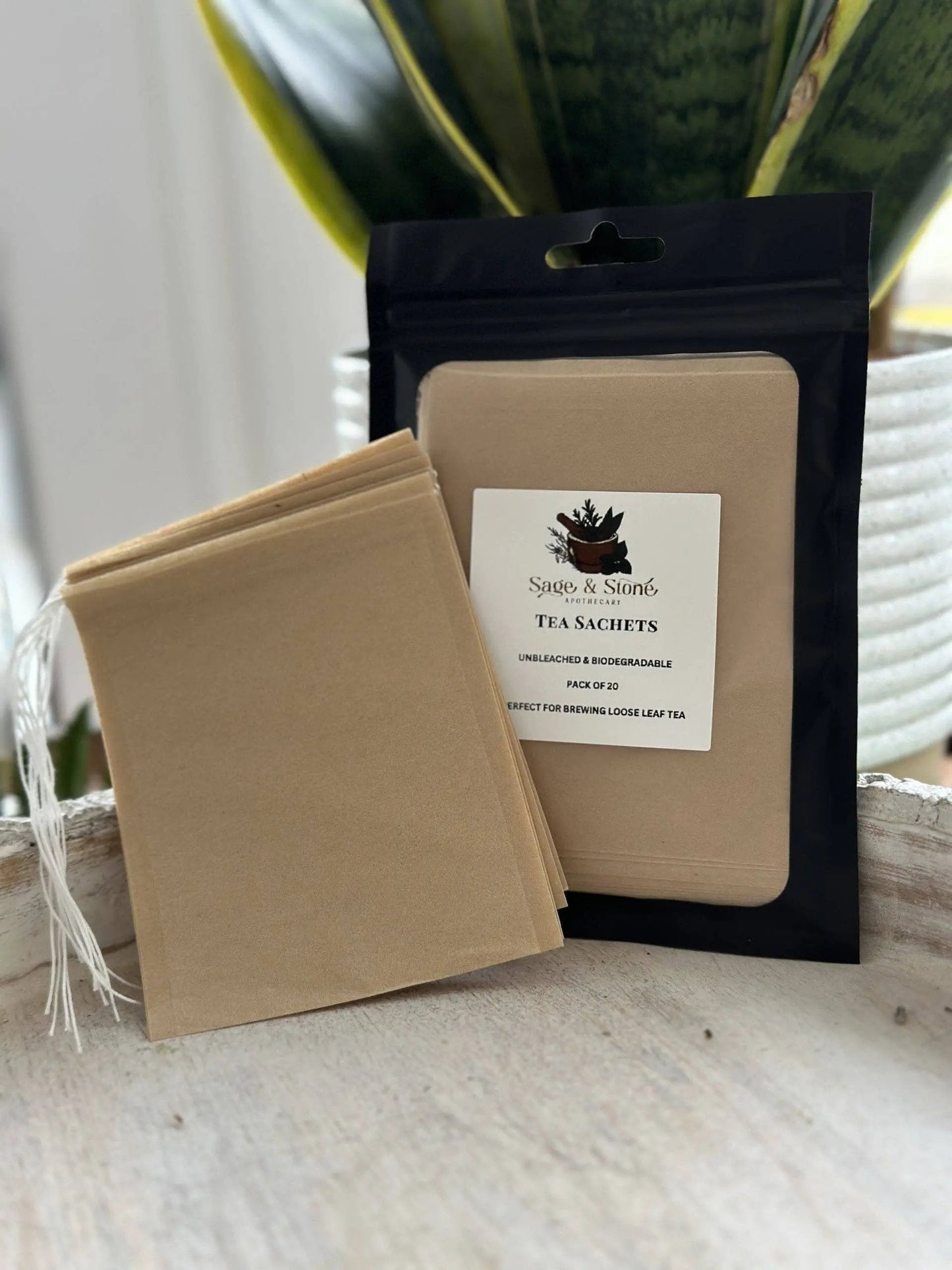 Tea sachets with a branded package on a wooden surface. -Clover's Charm