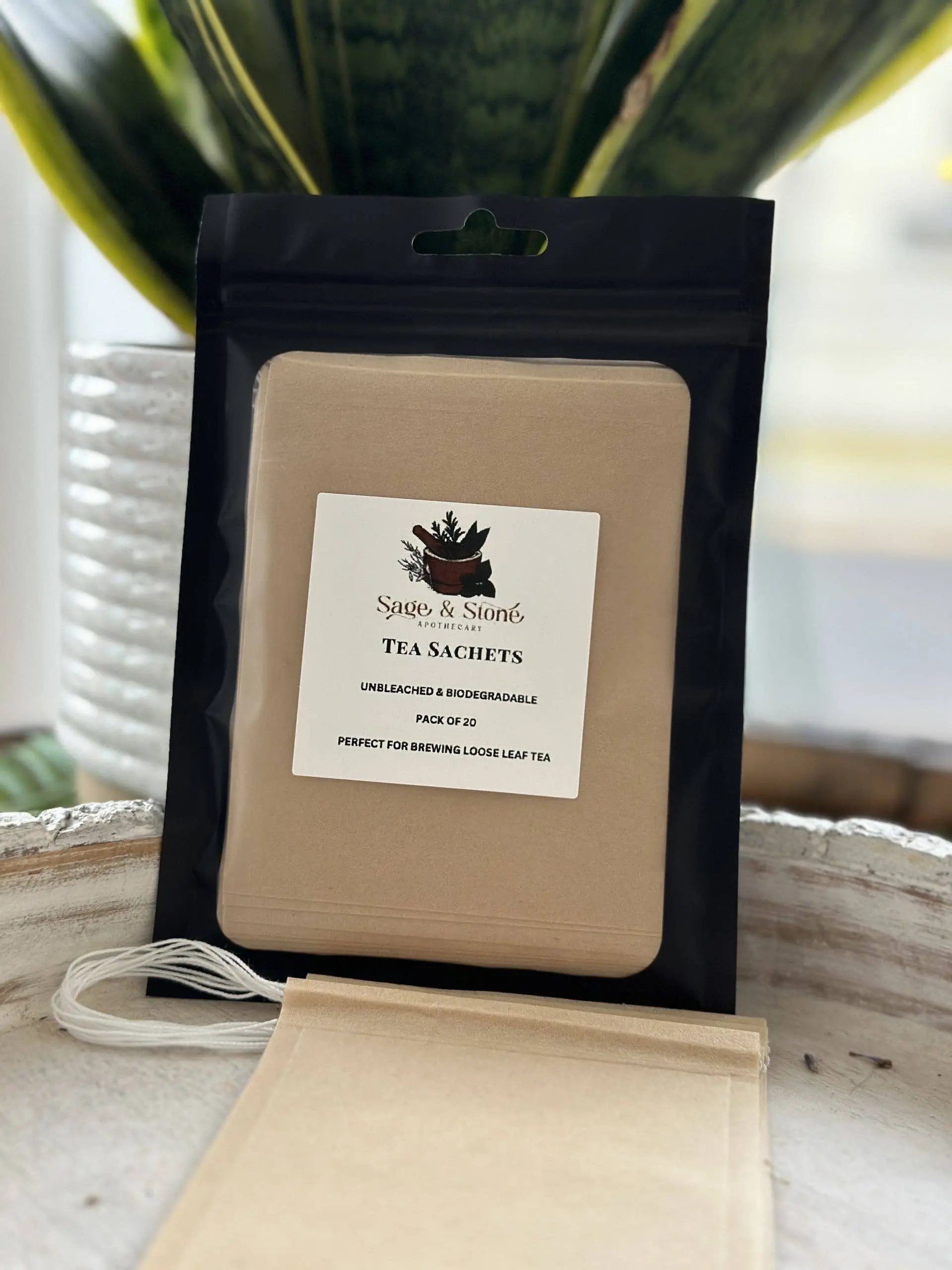 Tea sachets in a black package with a visible brand label on a wooden surface. -Clover's Charm