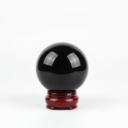 Black crystal ball on a red stand with a blurred background
