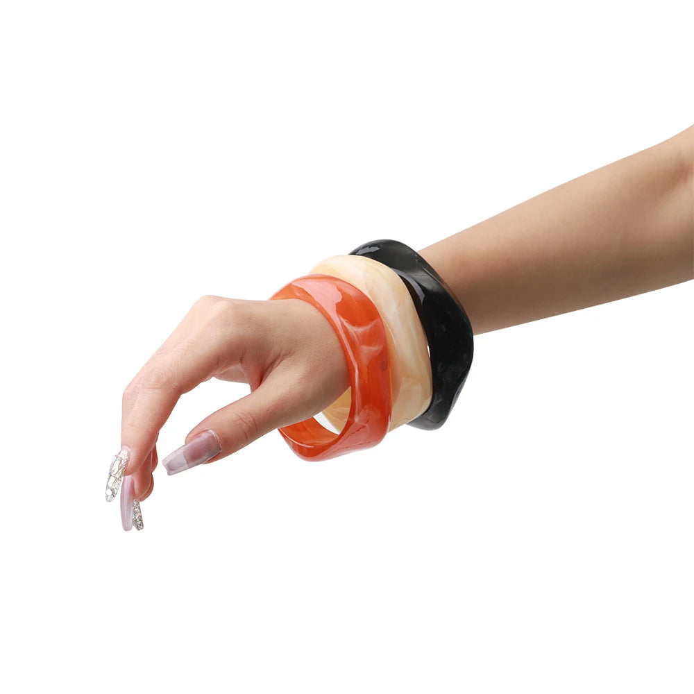 Hand wearing three colorful bangles on a white background