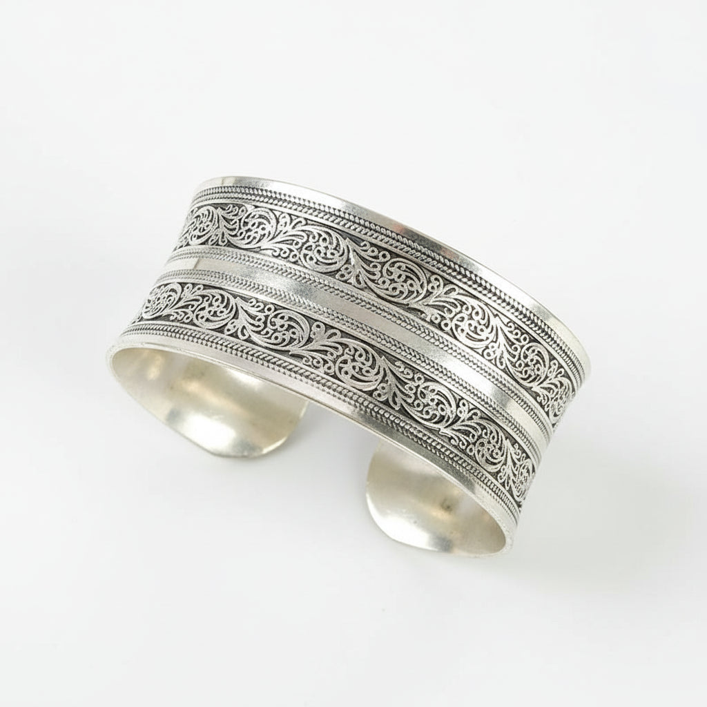 Silver bracelet with intricate patterns on a wooden surface