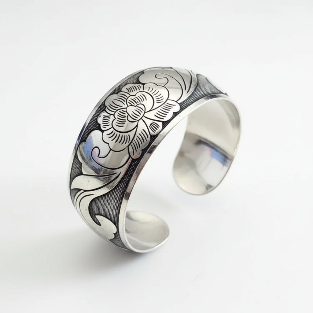 Silver bracelet with floral design on a wooden stand