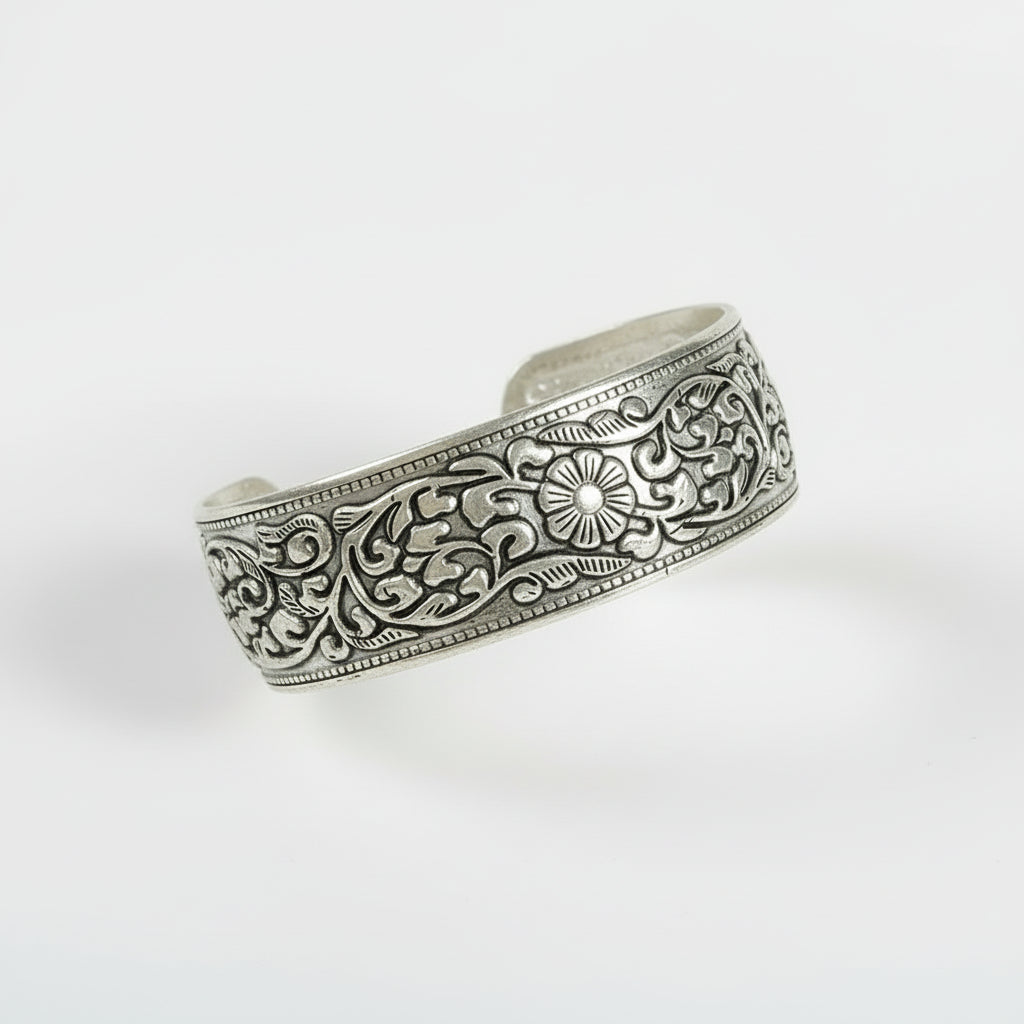 Silver bracelet with intricate designs on a wooden surface