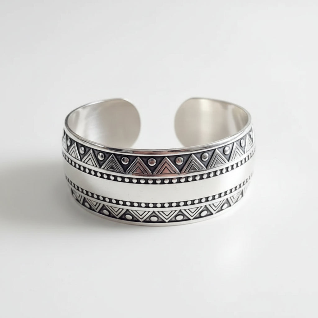 Silver bracelet with tribal patterns on a dark surface