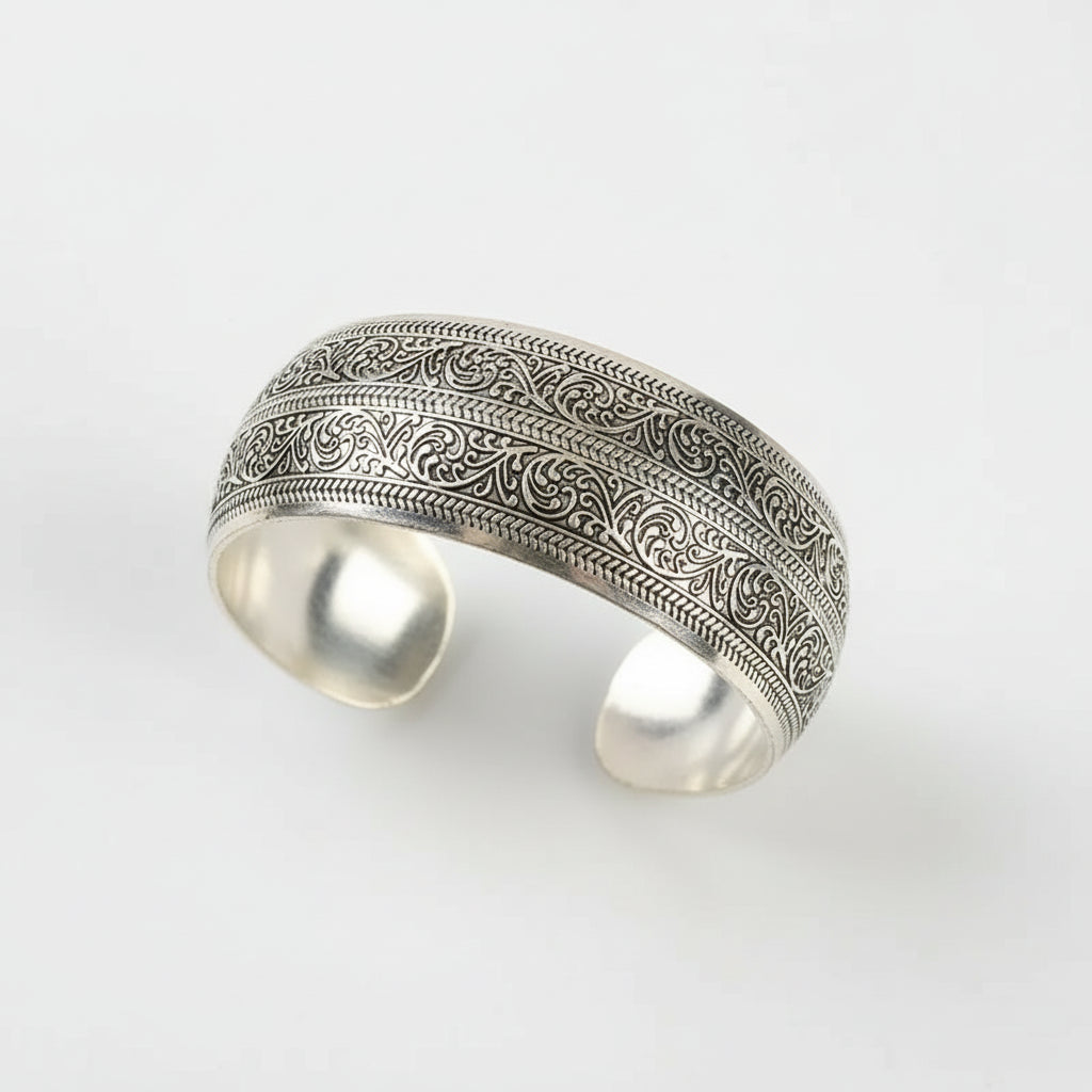 Silver bracelet with intricate patterns on a wooden surface