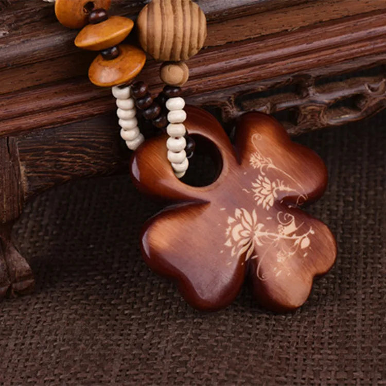 Wooden clover flower-shaped pendant with engraved design on a wooden surface