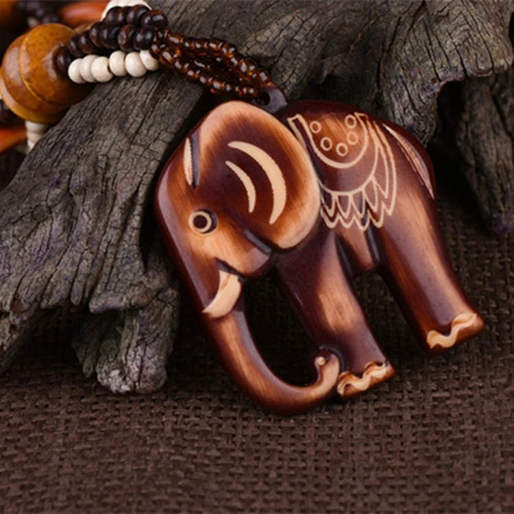 Wooden elephant pendant with intricate carvings on a textured surface