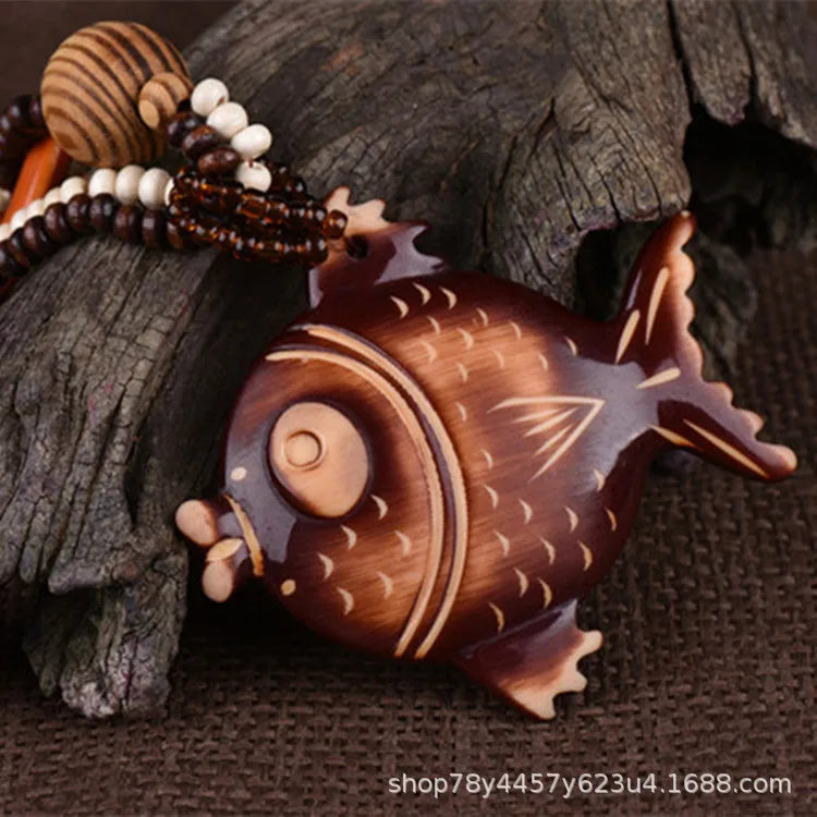 Wooden fish-shaped object with beads on a wooden surface