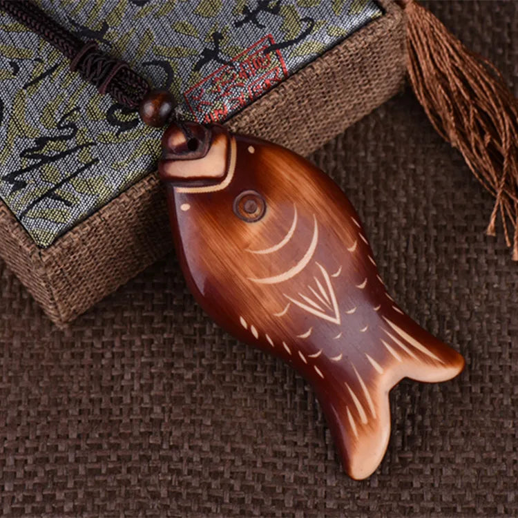 Wooden fish-shaped pendant on a textured fabric background