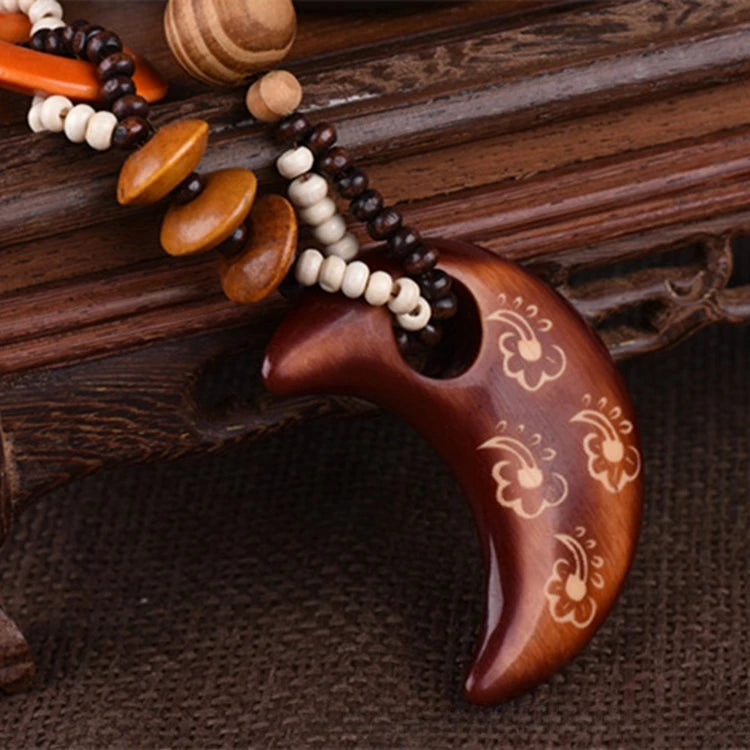 Wooden crescent moon pendant with bead necklace on a wooden surface