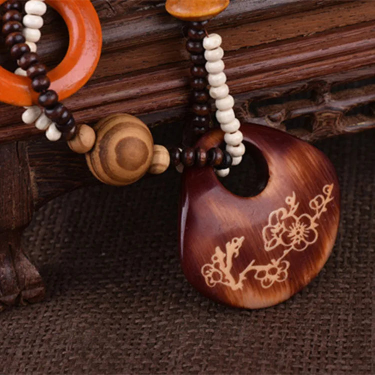 Wooden pendant with floral engraving on a wooden surface