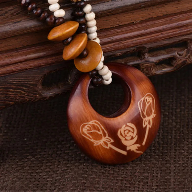 Round Wooden pendant roses, with bead necklace on a wooden surface
