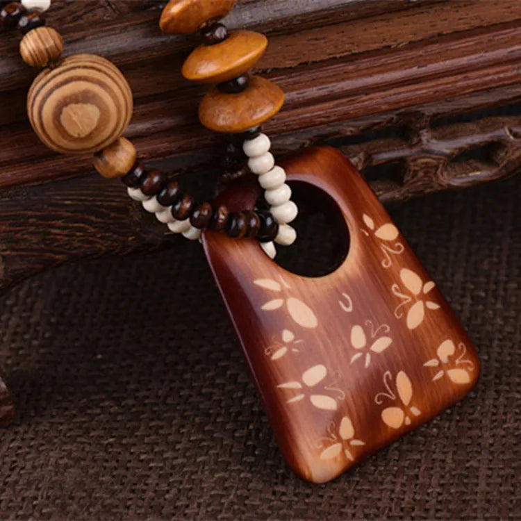 Wooden pendant with butterflies on it and bead chain on a wooden background