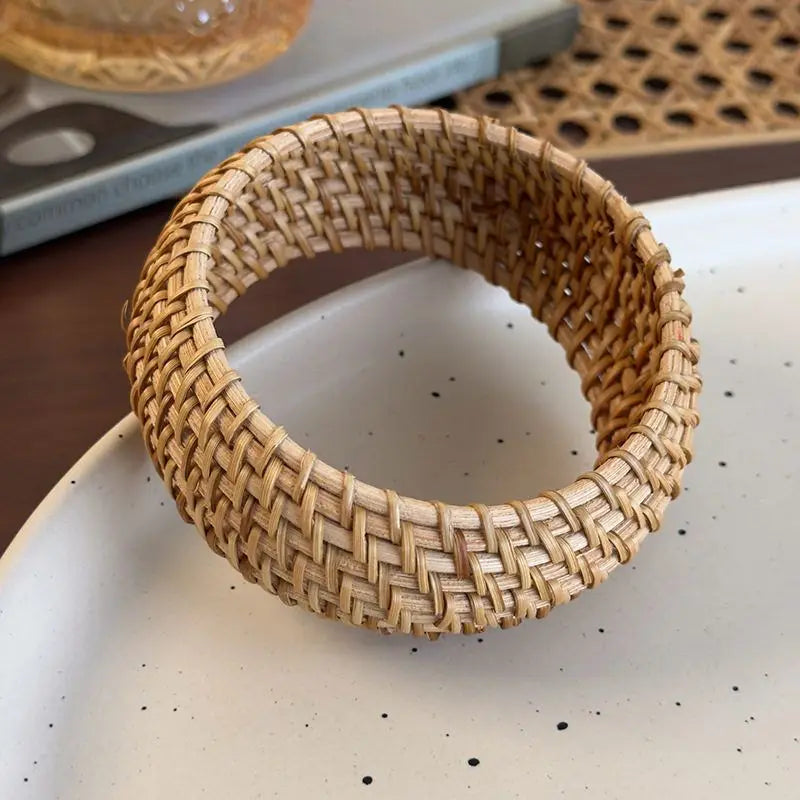 Woven rattan bangle bracelet on a speckled surface