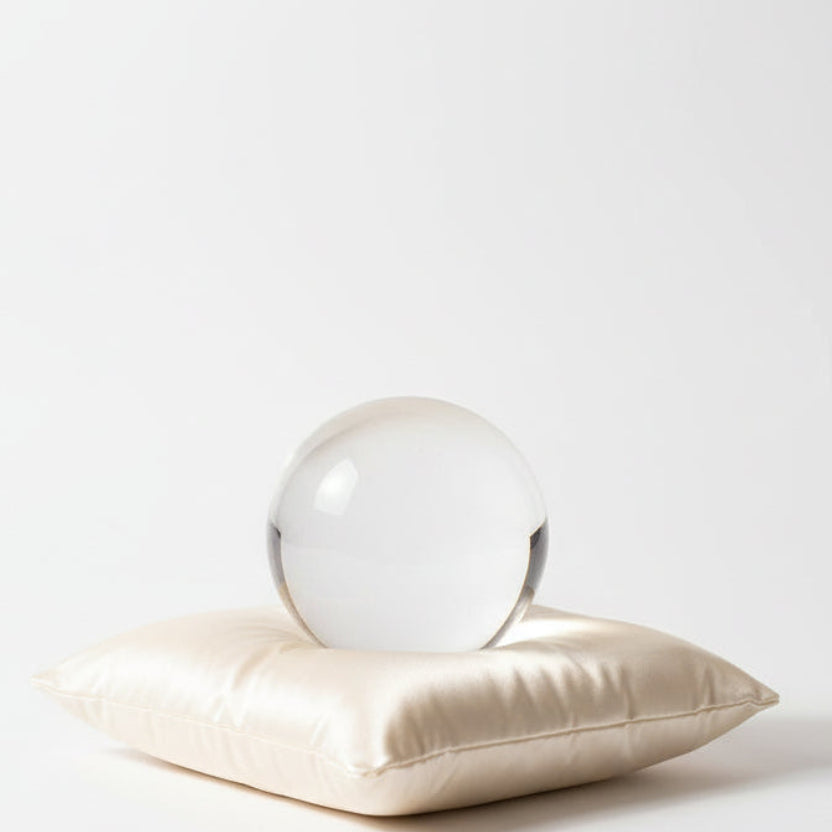 Clear glass sphere on a beige cushion against a white background
