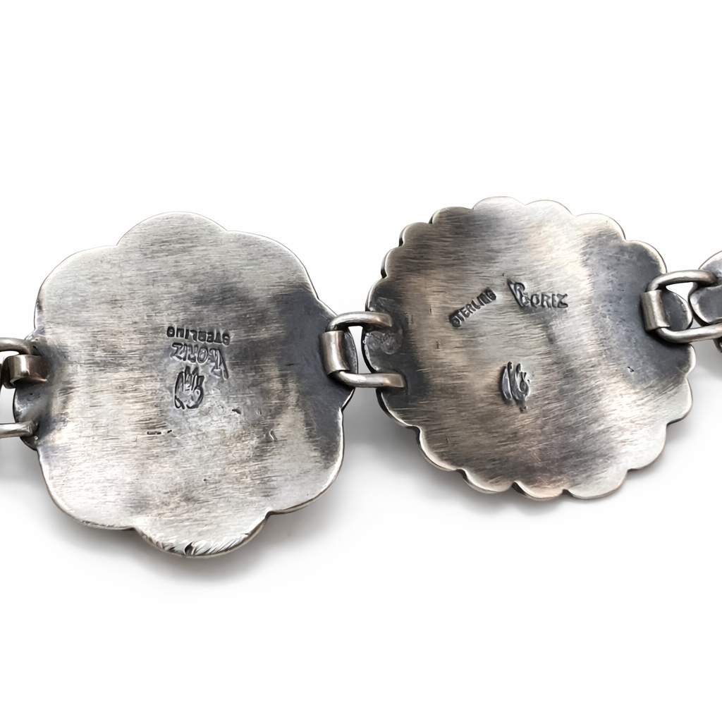 Close-up of a silver bracelet with hallmark V Coriz designs on a white background