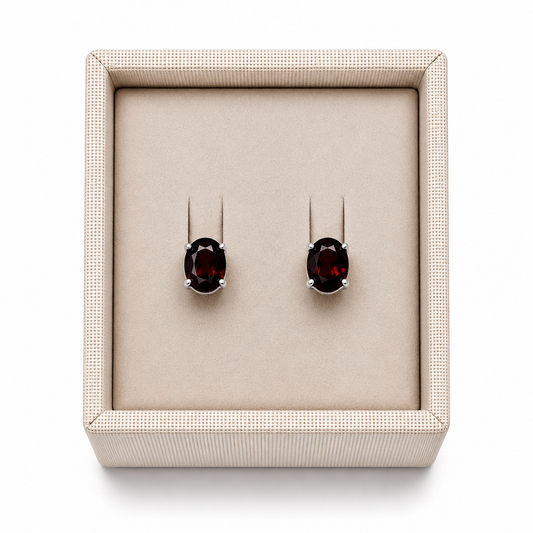Garnet sterling silver oval stud earrings in a display box on a white background. - Clover's Charm