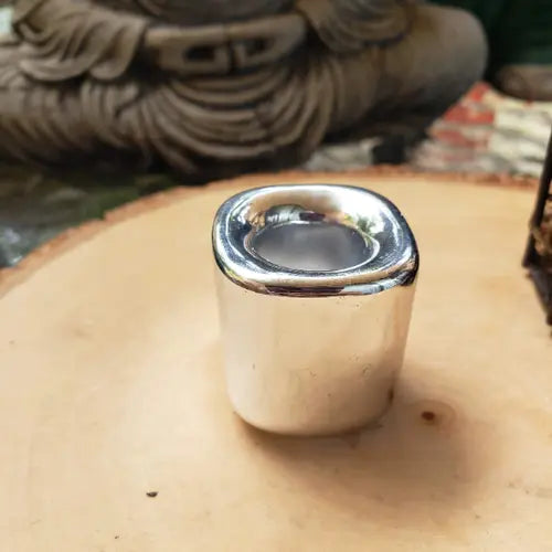 Silver cylindrical object on a wooden surface with a blurred background 
- Clover's Charm
