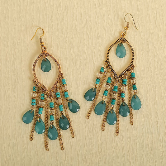 Pair of gold and turquoise chandelier earrings on a beige background