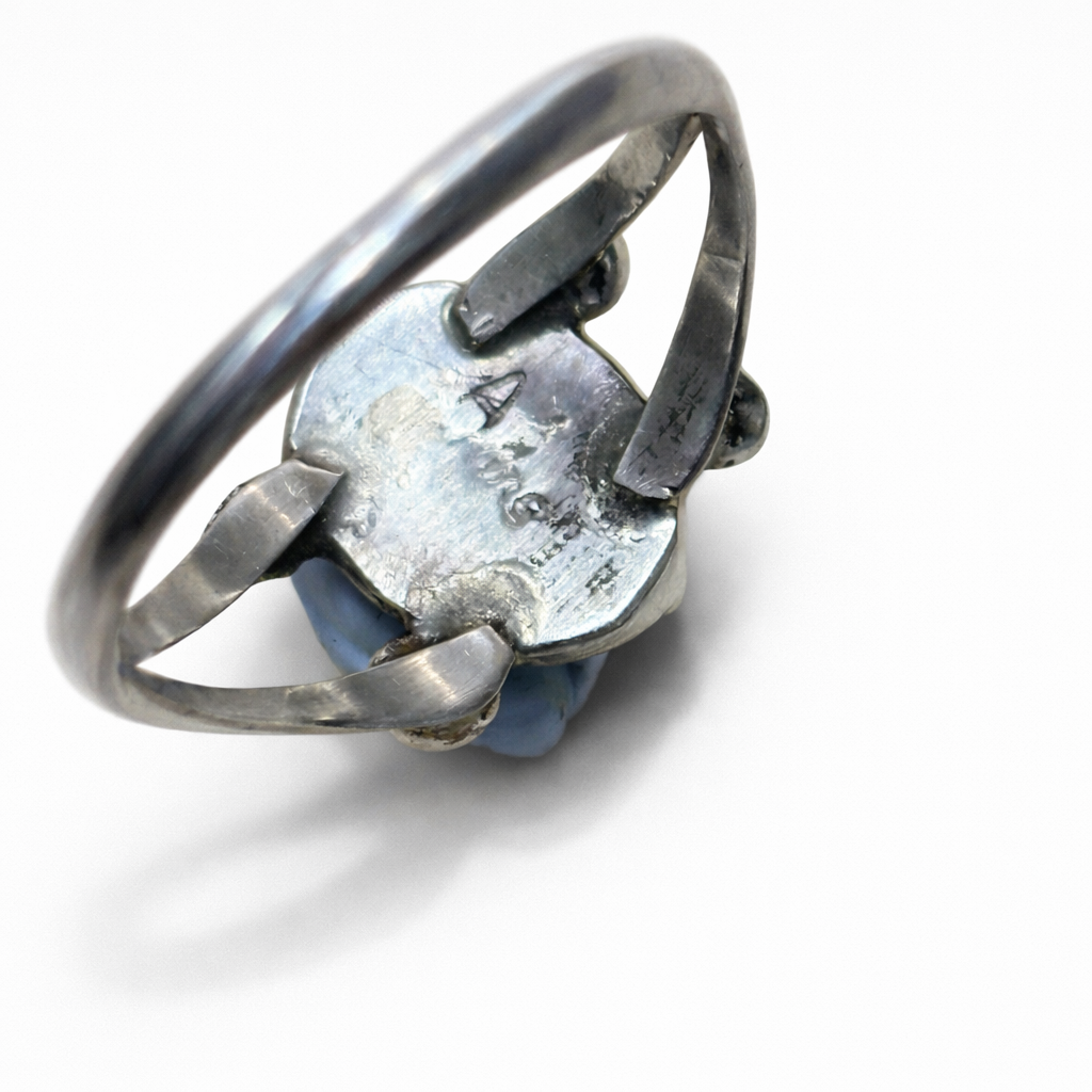 Silver ring with a textured stone on a white background