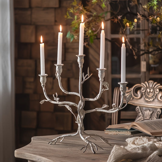 Tree branch style metal candelabra holding five lit taper candles displayed on a rustic table with books and vintage home decor accents