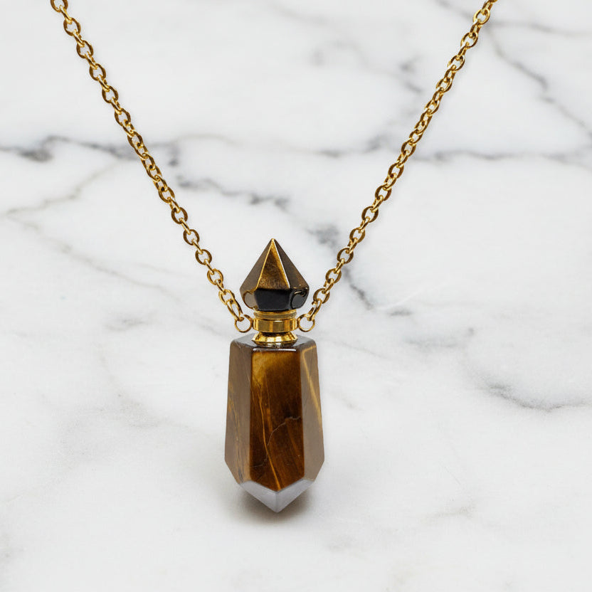 Natural Tigers Eye Gems Stone Faceted Prism Perfume Bottle Pendants With gold plated chain on a white marble surface. 