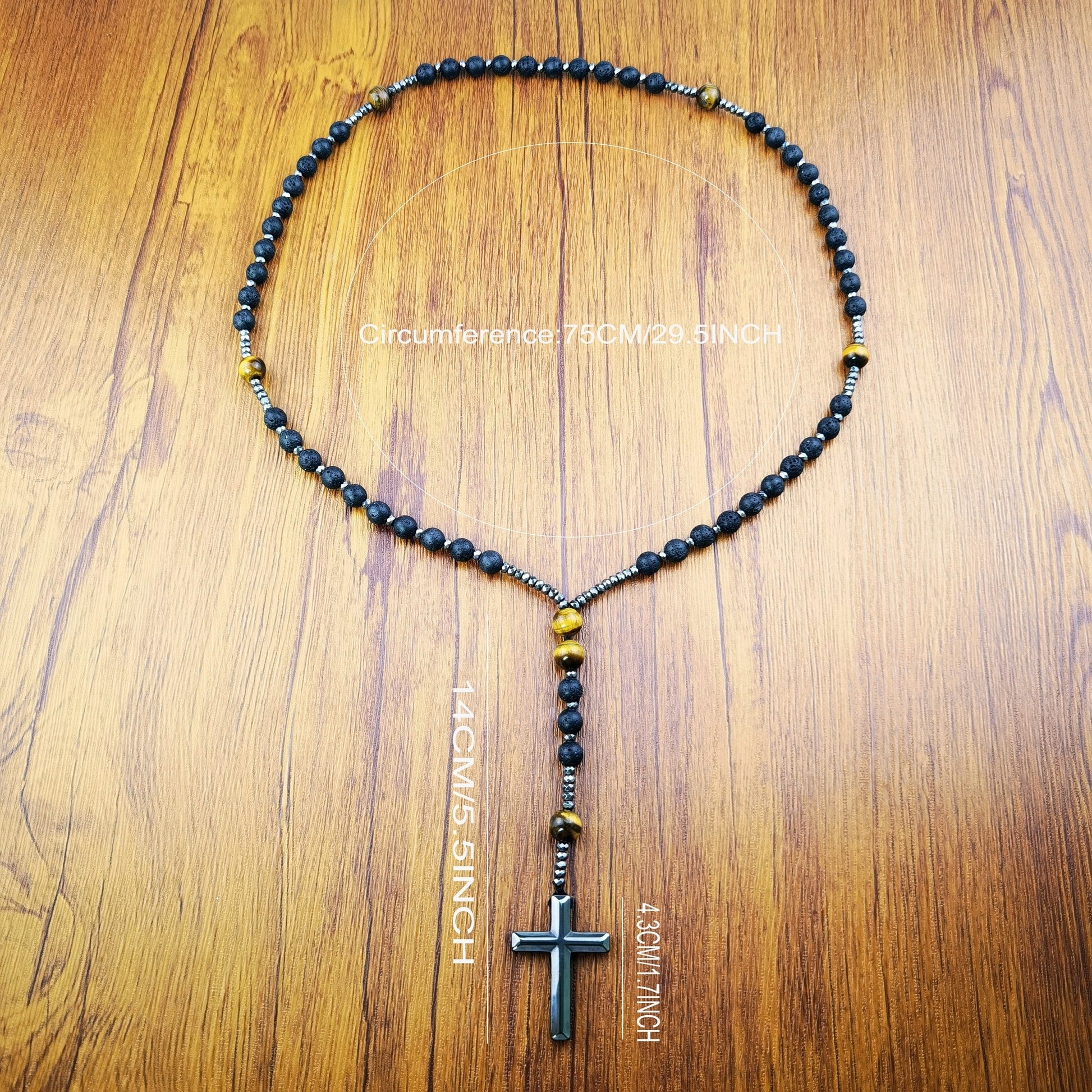 Necklace with black beads and a cross pendant on a wooden surface with measurements