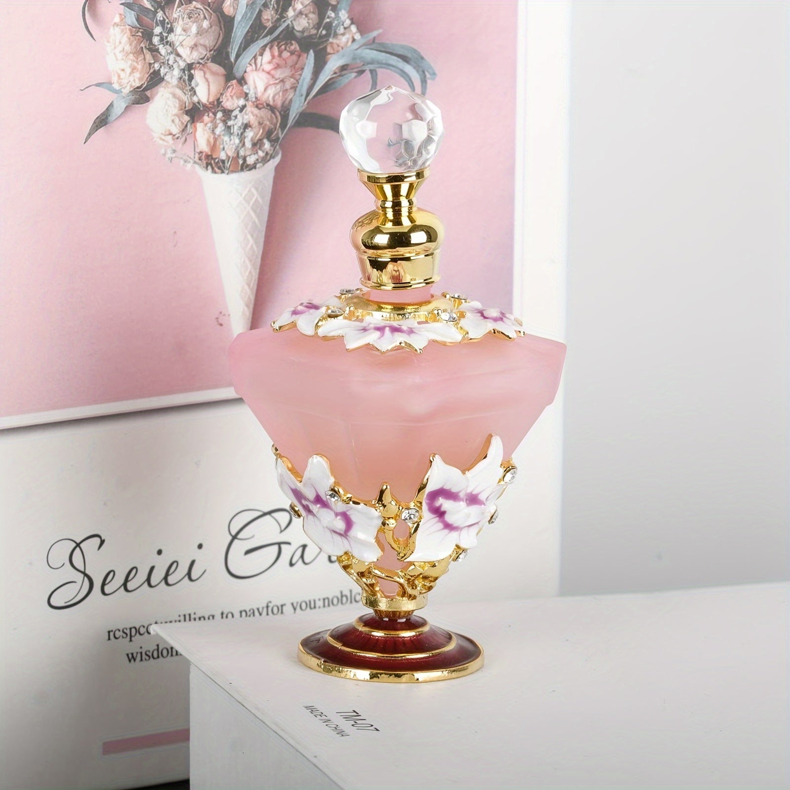 Pink diamond style glass perfume bottle with floral detail styled on vanity surface