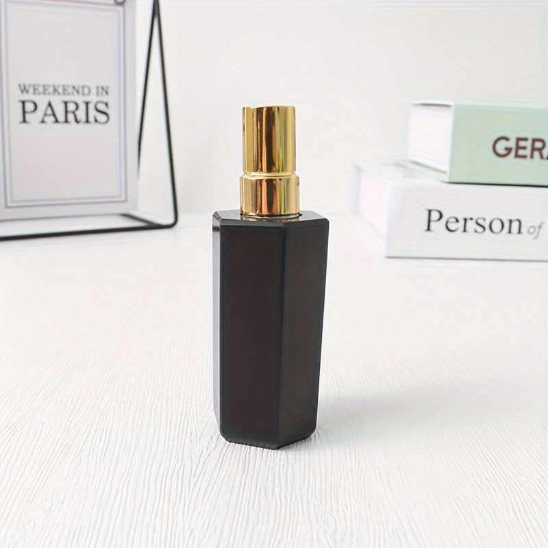 A black refillable natural crystal stone perfume bottle with stainless steel spray pump on a white background by a stack of books.