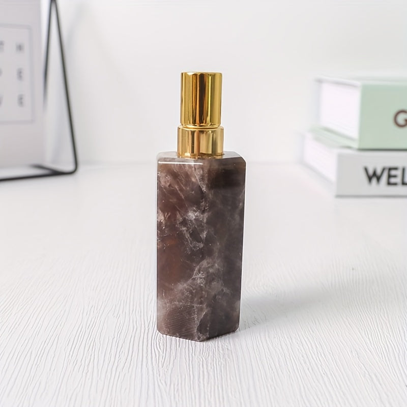 A brown refillable natural crystal stone perfume bottle with stainless steel spray pump on a white background by a stack of books.