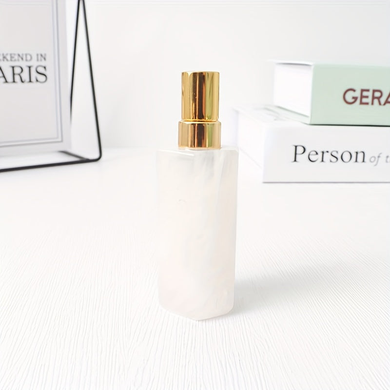 A clear refillable natural crystal stone perfume bottle with stainless steel spray pump on a white background by a stack of books.