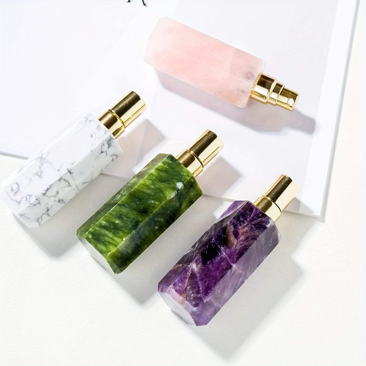 Refillable natural crystal stone perfume bottle in assorted crystal stones on a white surface.
